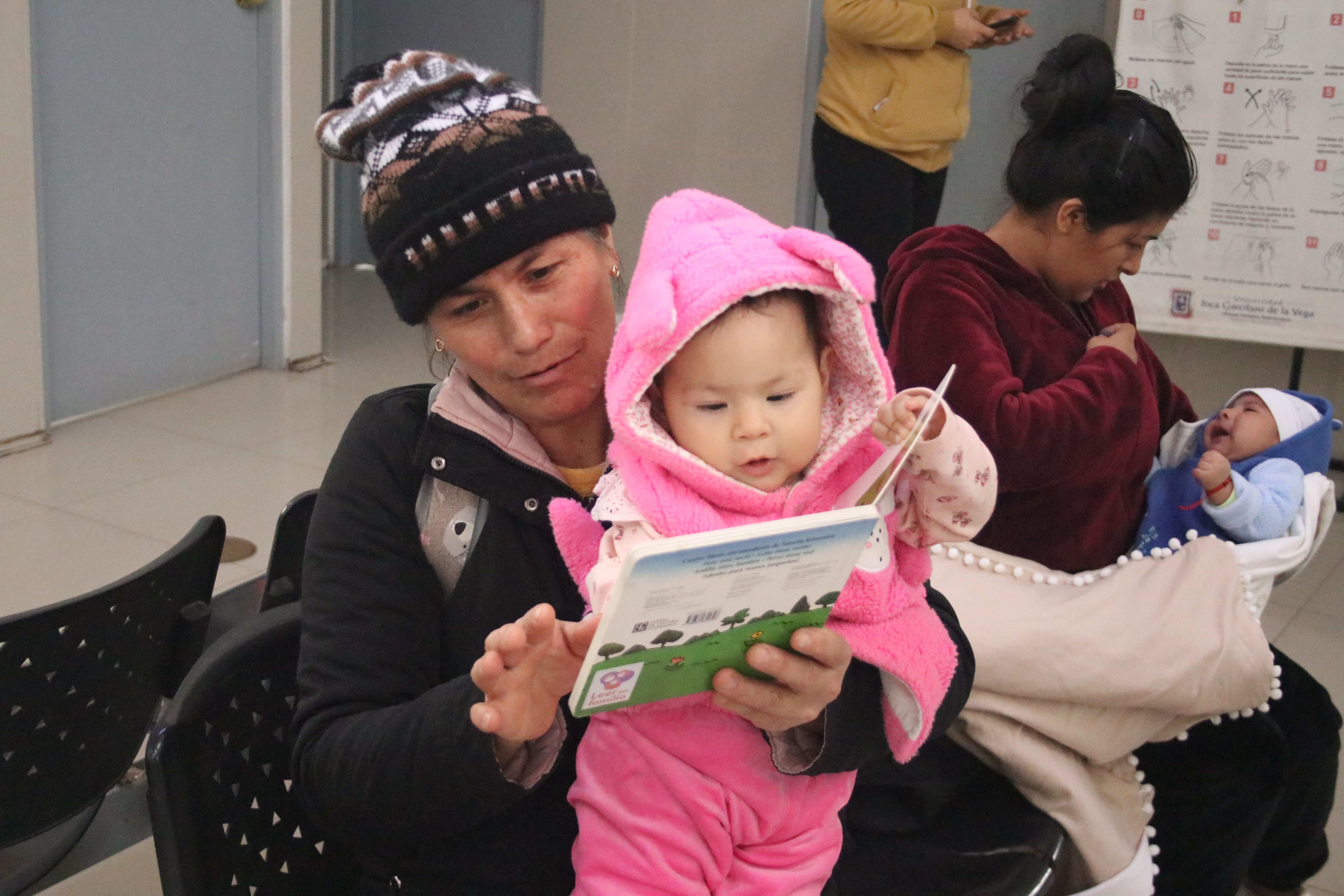 A baby in a pink jumper reading a book